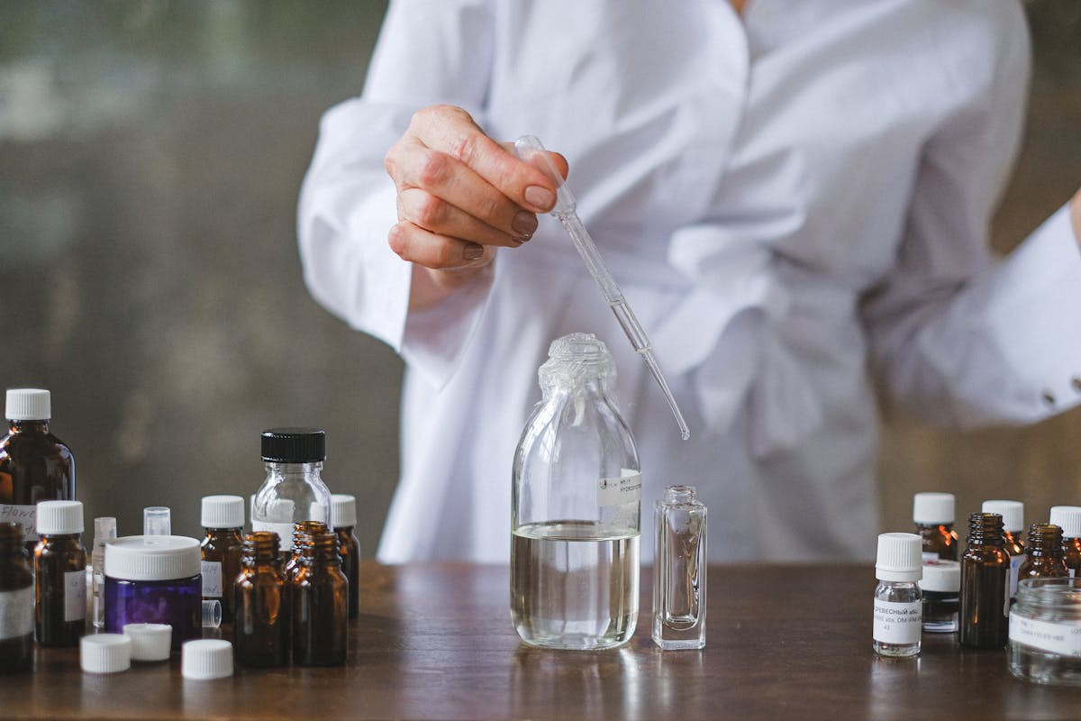 Scientist using a dropper to mix liquids in glass bottles, showcasing a laboratory setting.