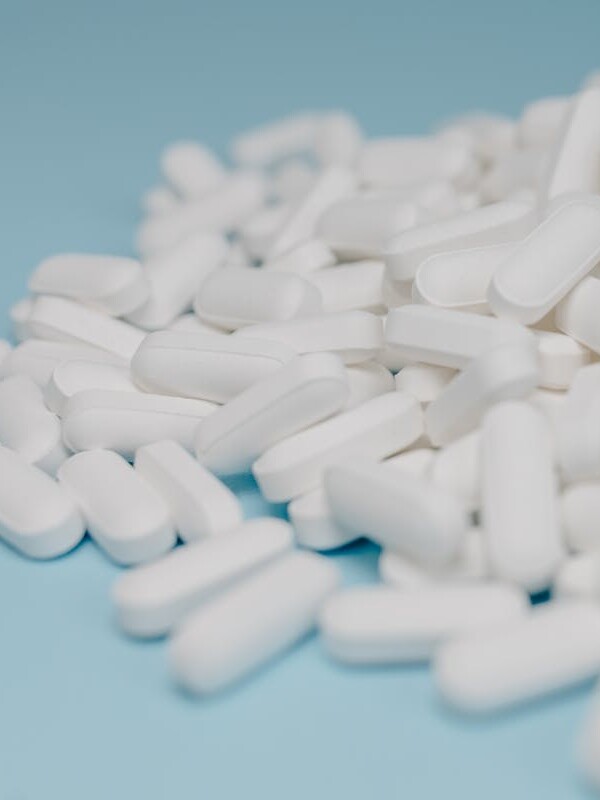 Close-up of white pills scattered on a blue background, focusing on pharmaceuticals.