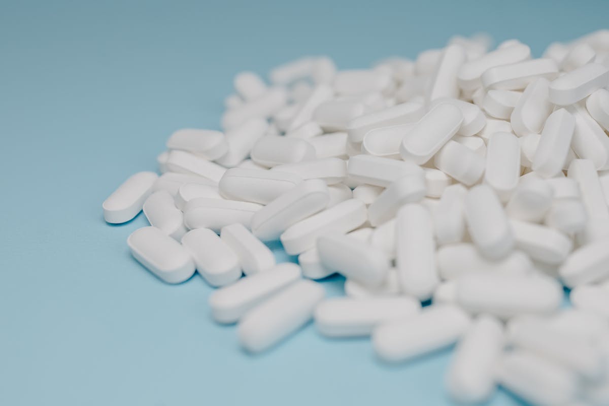 Close-up of white pills scattered on a blue background, focusing on pharmaceuticals.