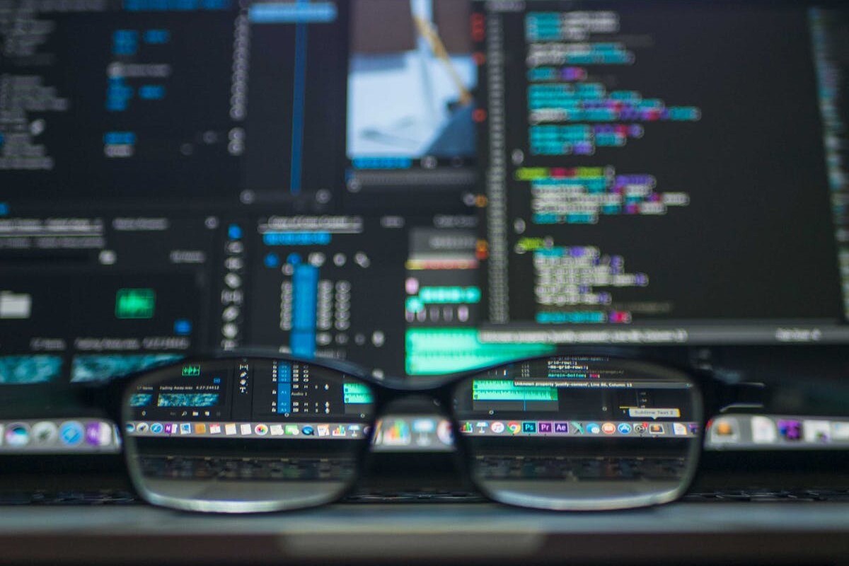 Eyeglasses reflecting computer code on a monitor, ideal for technology and programming themes.