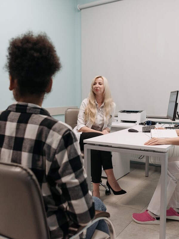 Doctors talking with patients during a medical appointment in a clinic office setting.