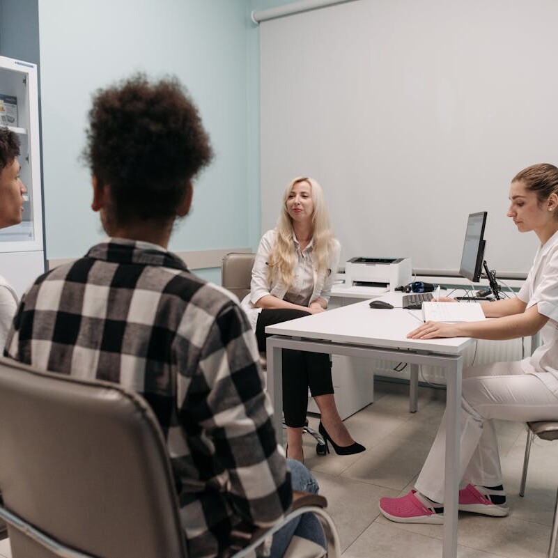 Doctors talking with patients during a medical appointment in a clinic office setting.